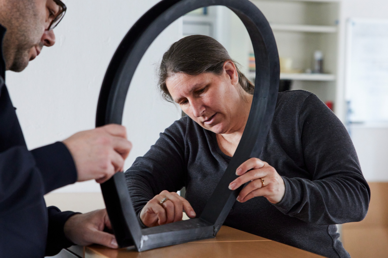 Two engineers inspecting a large rubber seal at a workbench, with one closely examining the joint for precision and fit.